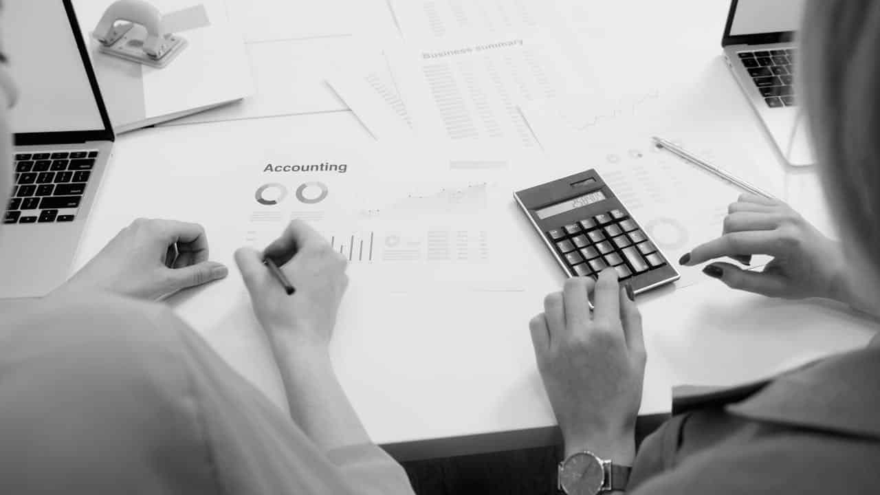Services Black and white office scene featuring accounting documents, calculator, and laptops.