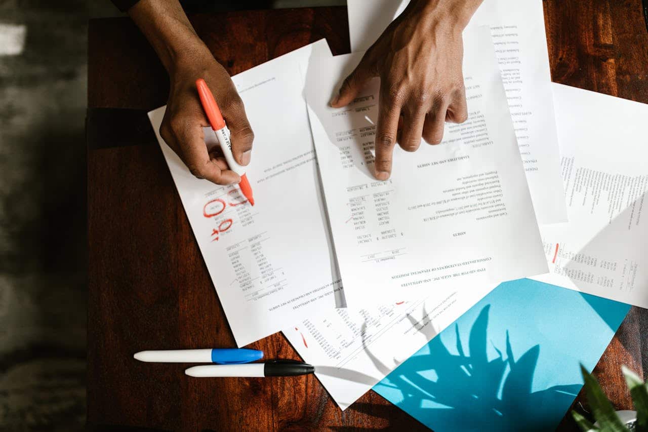 About Overhead view of hands highlighting financial documents on a desk.