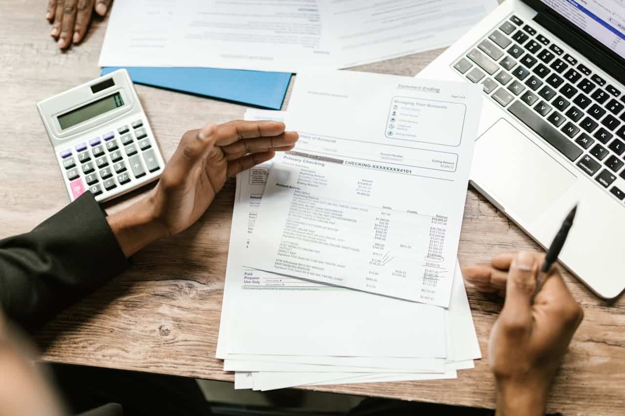 Services Hands holding financial documents with calculator and laptop on office desk, business analysis scene.